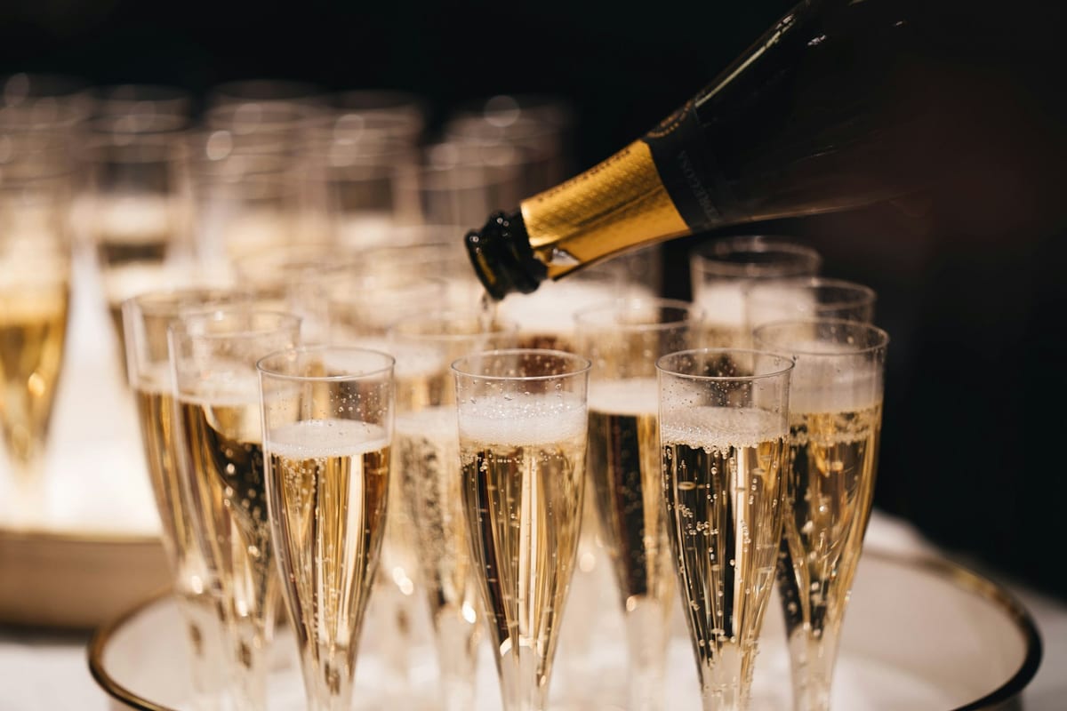 Champagne being poured into flutes on a tray at an event