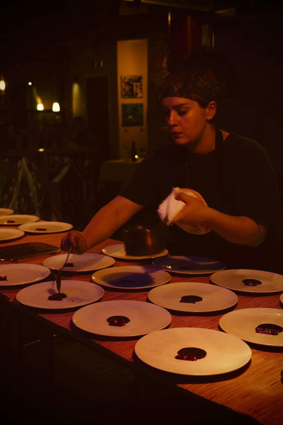 A chef finishing a row of plates in a restaurant kitchen