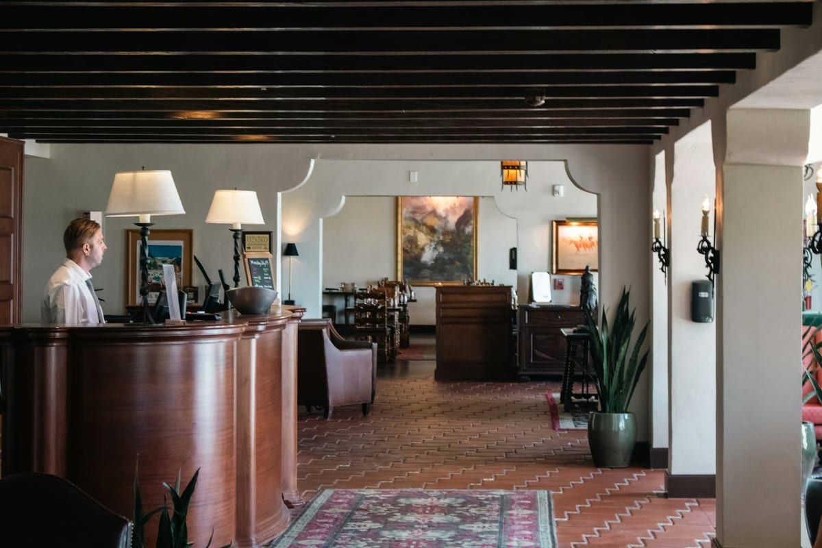 A receptionist at the front desk of a hotel lobby, ready for the first guests of the evening